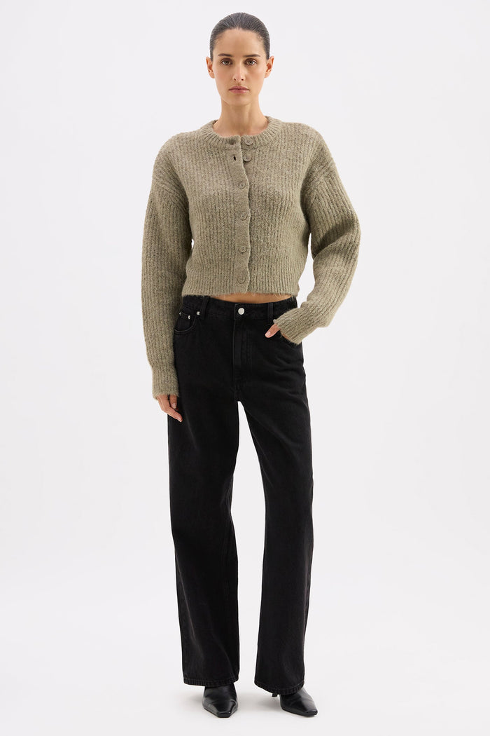 Woman wearing a textured cardigan and black pants on a white background