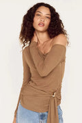 Woman wearing a brown top with a tie detail and blue jeans on a white background