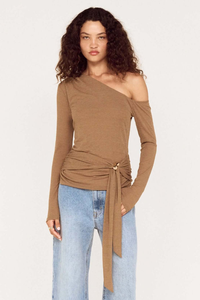 Woman wearing a brown off-shoulder top and blue jeans on a white background