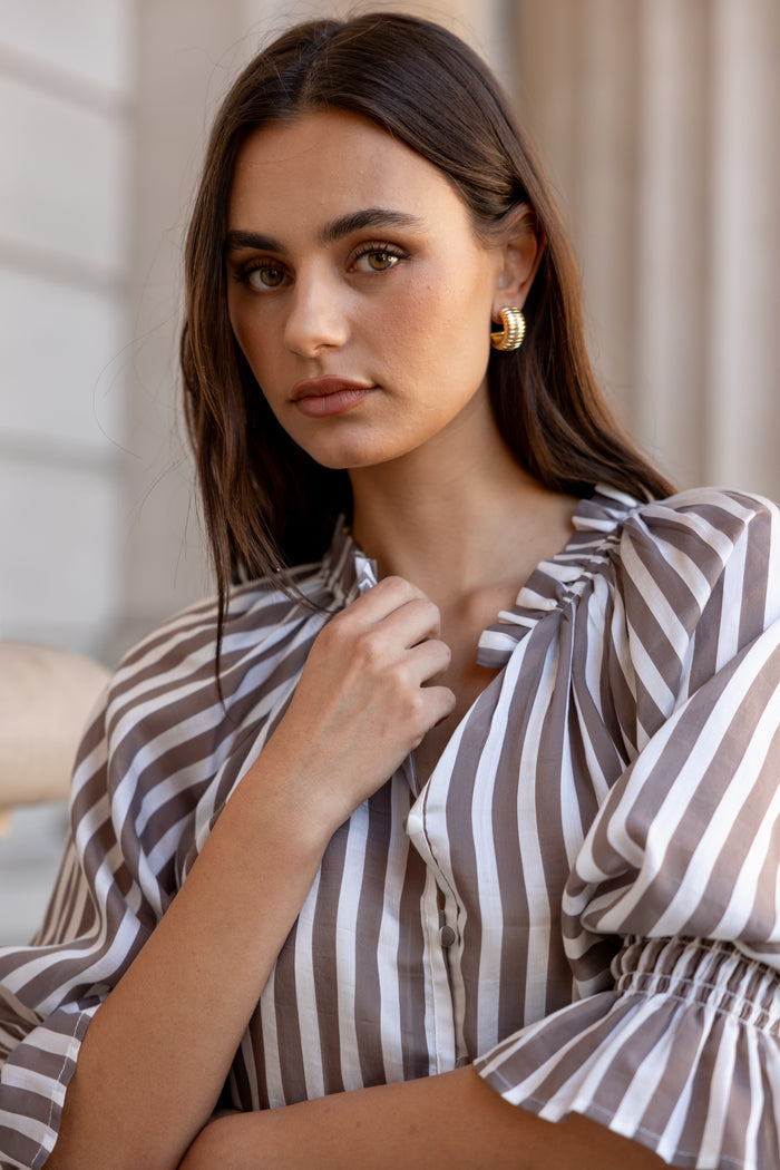 Woman wearing a striped blouse with a neutral background