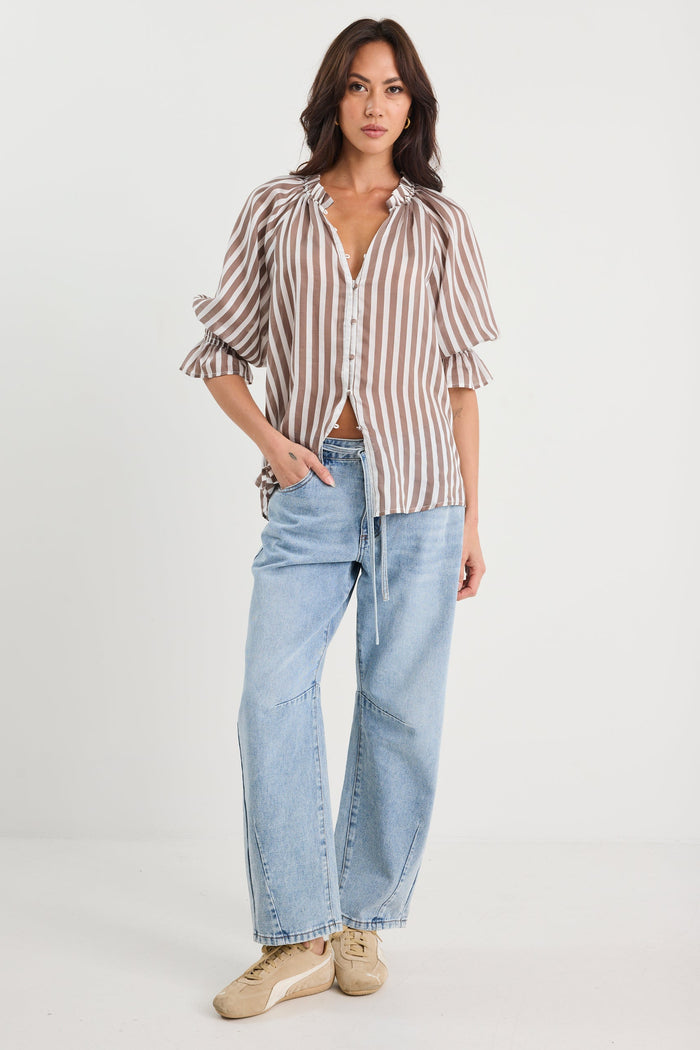 Woman wearing a striped shirt and light blue jeans on a white background