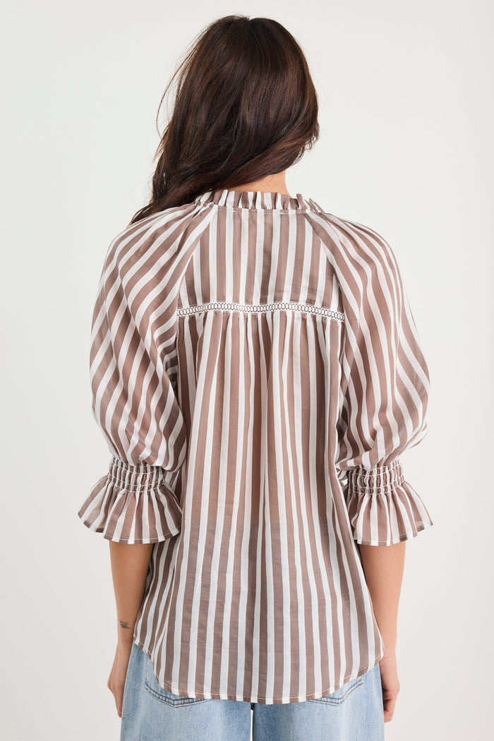 Woman wearing a striped shirt with balloon sleeves on a plain background