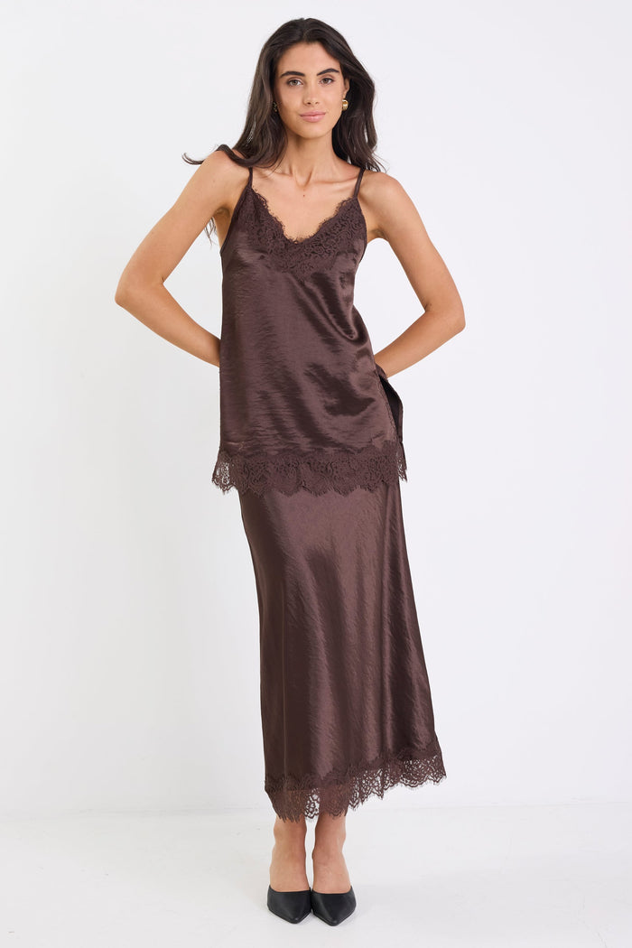 Woman wearing a brown satin slip dress on a white background