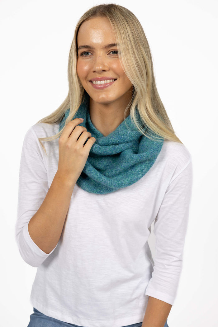 Woman wearing a teal scarf around her neck on a white background