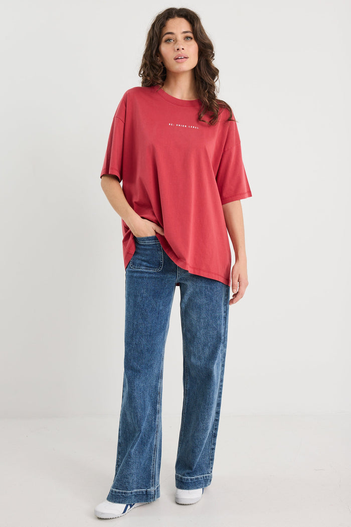 Woman wearing a red oversized t-shirt and blue jeans on a white background