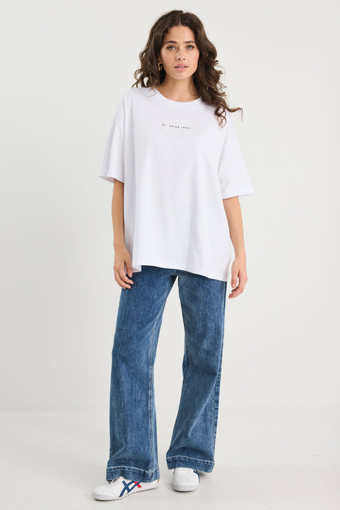 Woman wearing a white oversized t-shirt and blue jeans on a white background