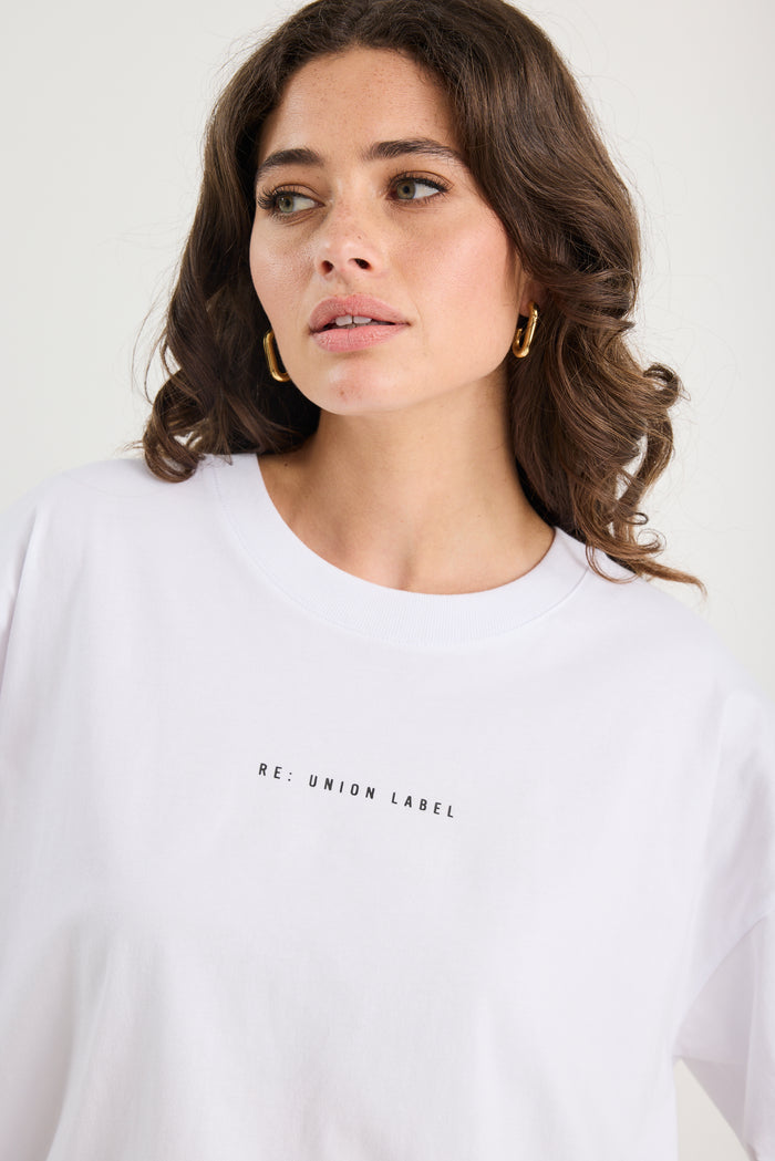Woman wearing a white t-shirt with text on a plain background