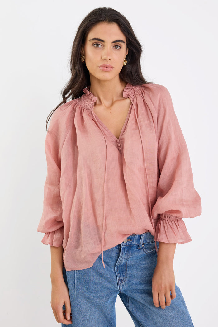 Woman wearing a pink blouse and blue jeans on a white background