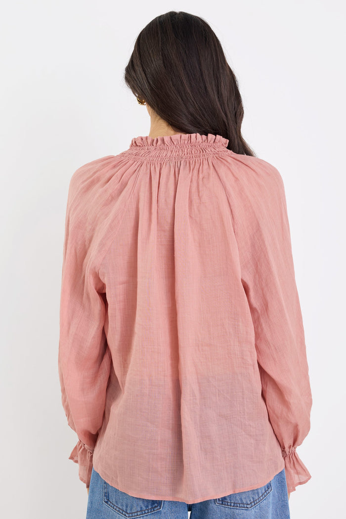 Person wearing a pink blouse and blue jeans on a white background