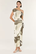 Woman wearing a one-shoulder dress with a leaf pattern on a white background