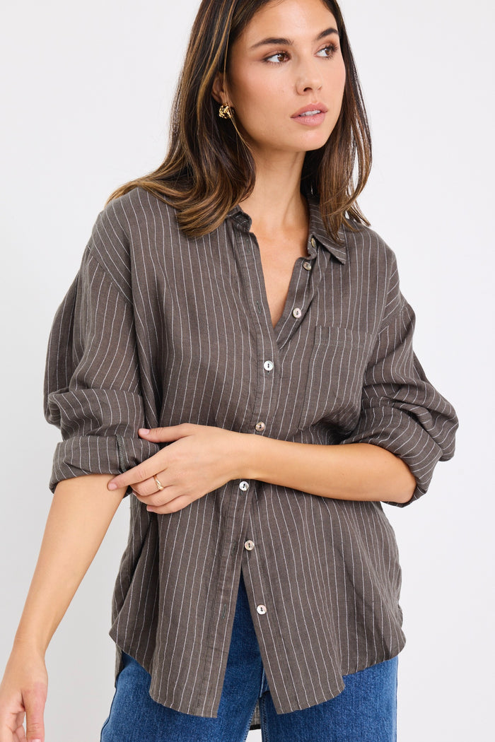 model wears a khaki white stripe shirt with dark blue jeans