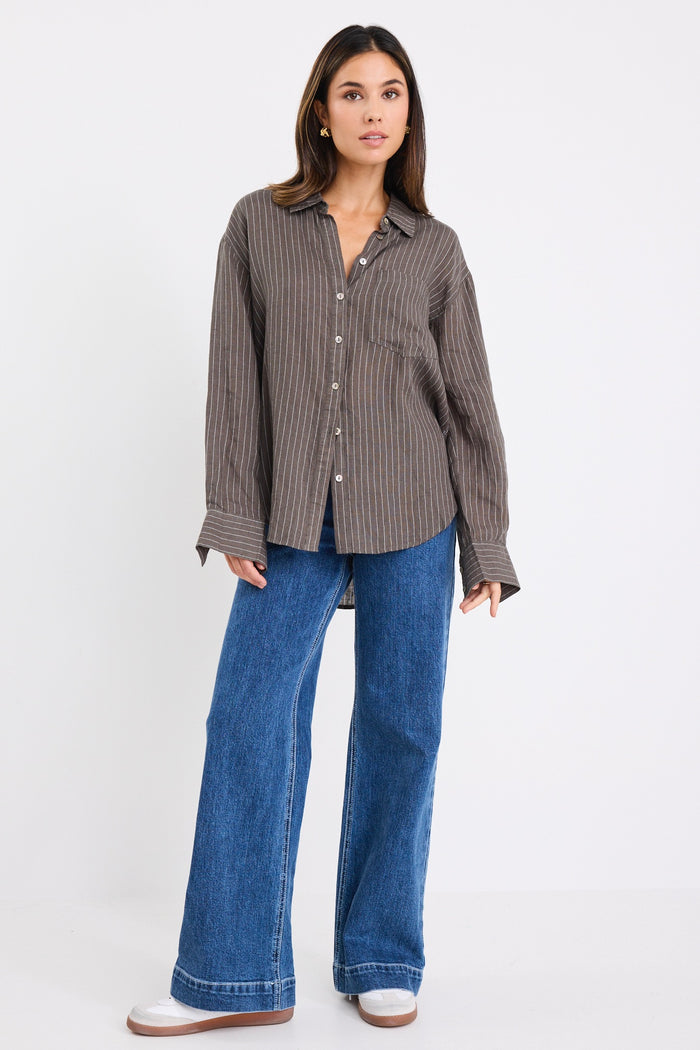 model wears a khaki white stripe shirt with dark blue jeans