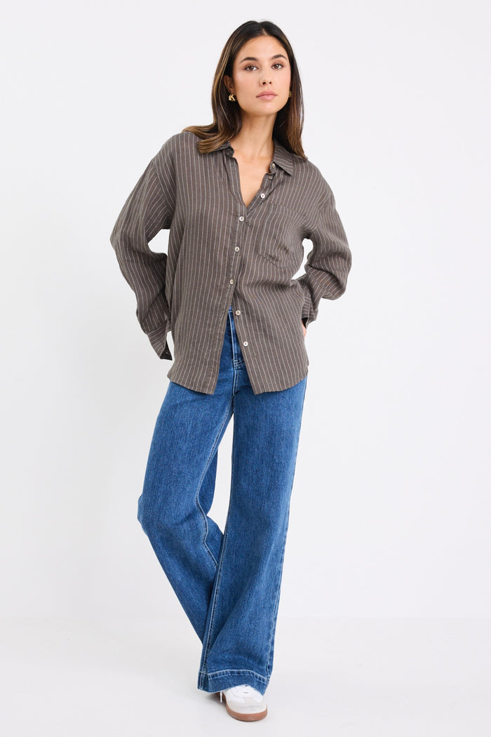 model wears a khaki white stripe shirt with dark blue jeans