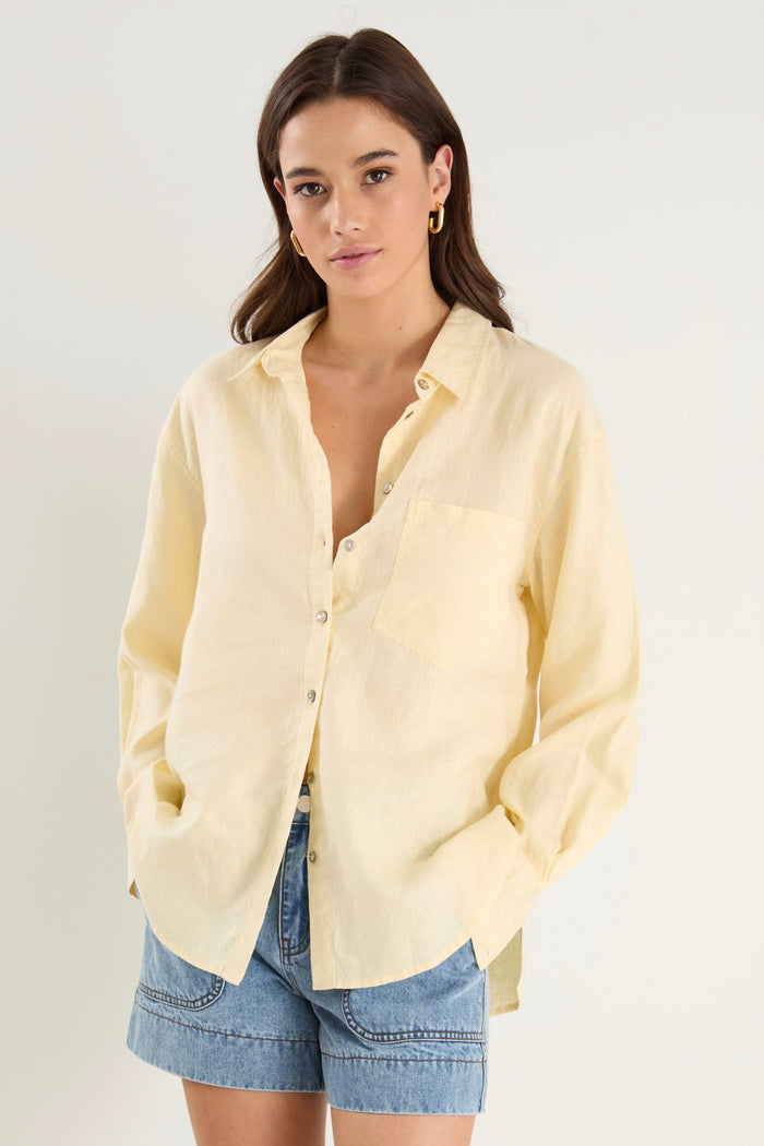 Model wears a yellow linen shirt with denim shorts and white sneakers