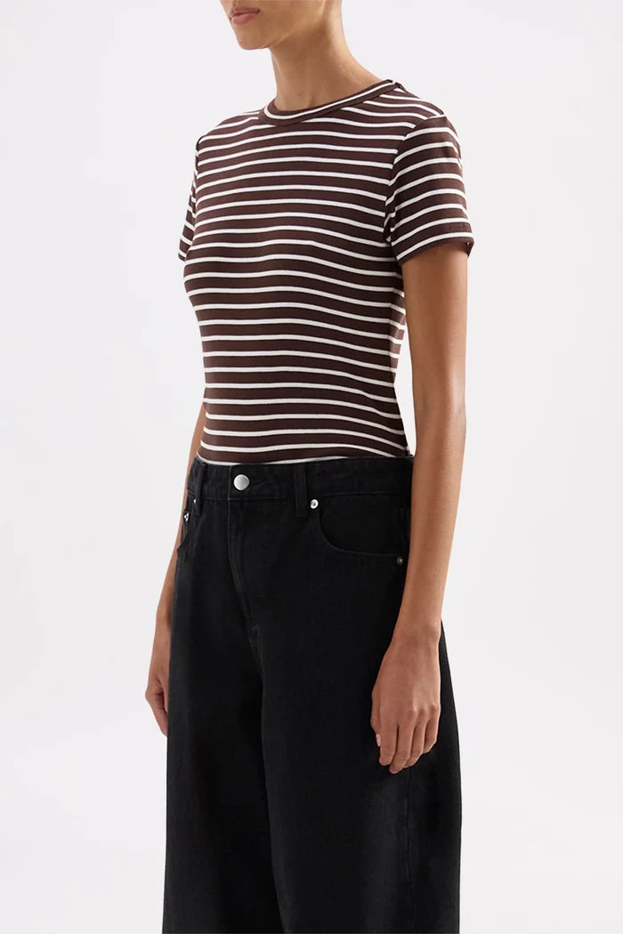 A model wearing a short-sleeve crewneck t-shirt with thin brown and white horizontal stripes, paired with black wide-leg jeans, against a plain white studio background.