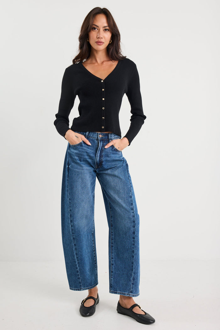 Woman wearing a black cardigan and blue jeans on a white background