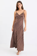Woman wearing a chocolate brown satin midi dress with white polka dots, adjustable spaghetti straps, and a bias-cut silhouette, standing against a white background.