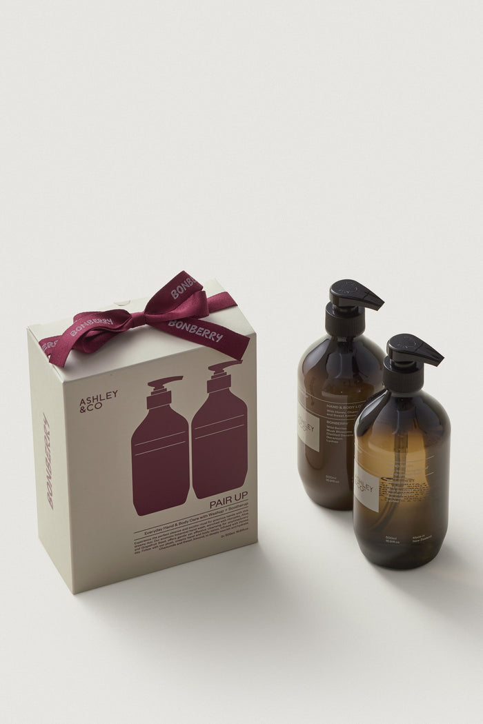 Two brown bottles with black caps and a matching box with a red bow on a white background.