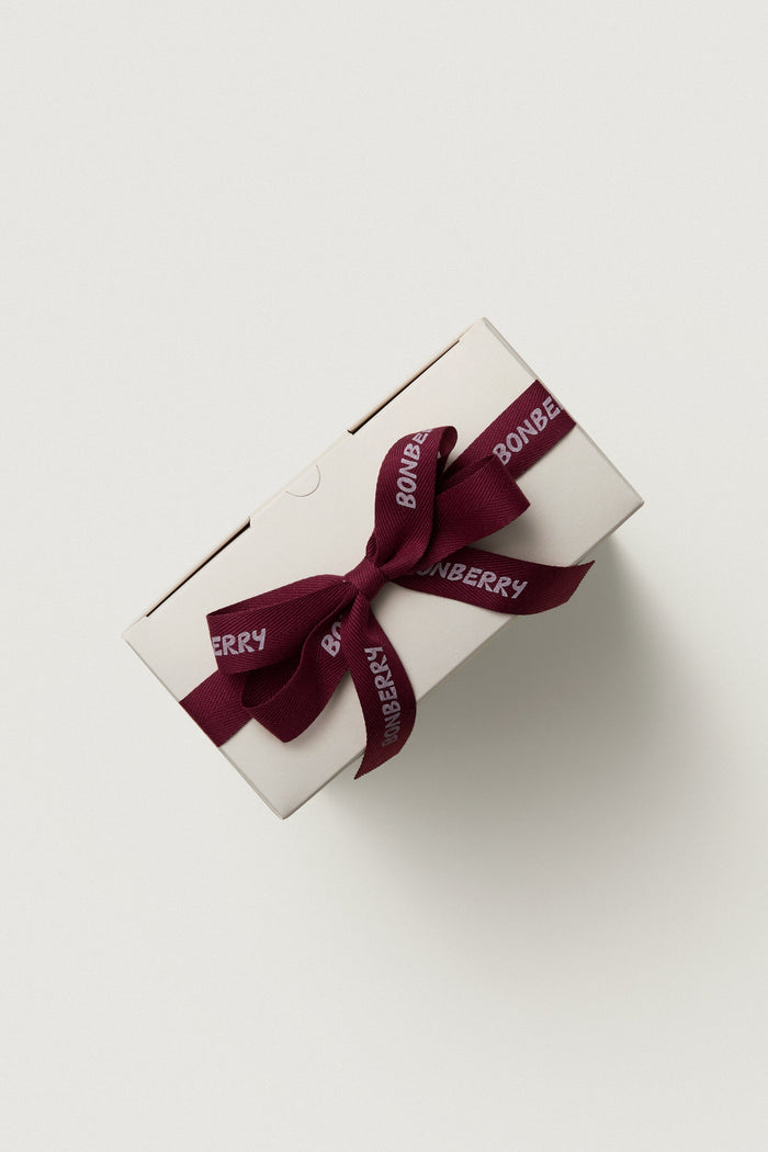 White gift box with a red ribbon on a light gray background