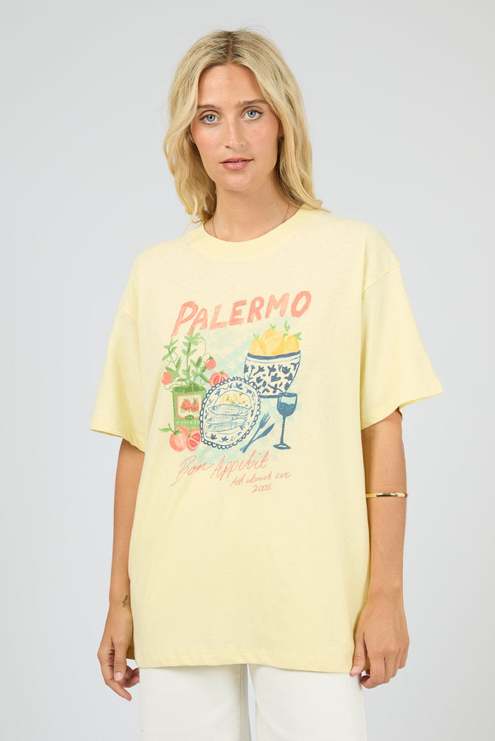 Woman wearing a yellow t-shirt with a graphic design on a plain background