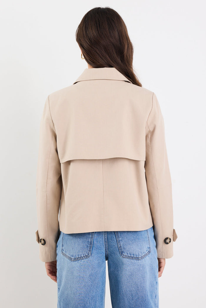 Person wearing a beige jacket and blue jeans against a white background
col_pattern