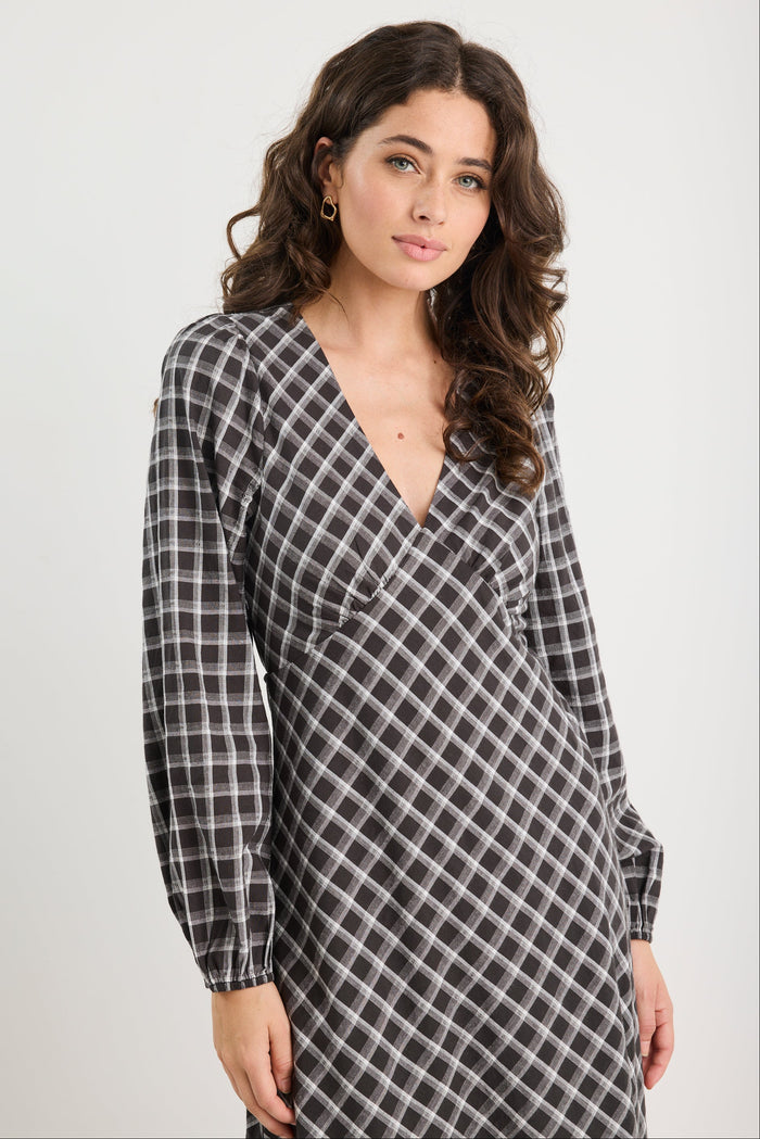 Woman wearing a black and white checkered dress against a plain background