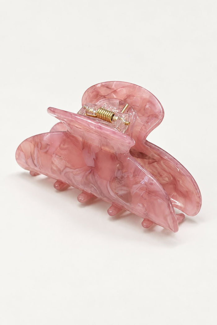 A pink marbled hair claw clip with a gold-tone metal spring and posts, shown on a clean white background.