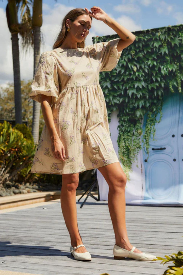 Woman wearing a cream floral mini dress with puff sleeves