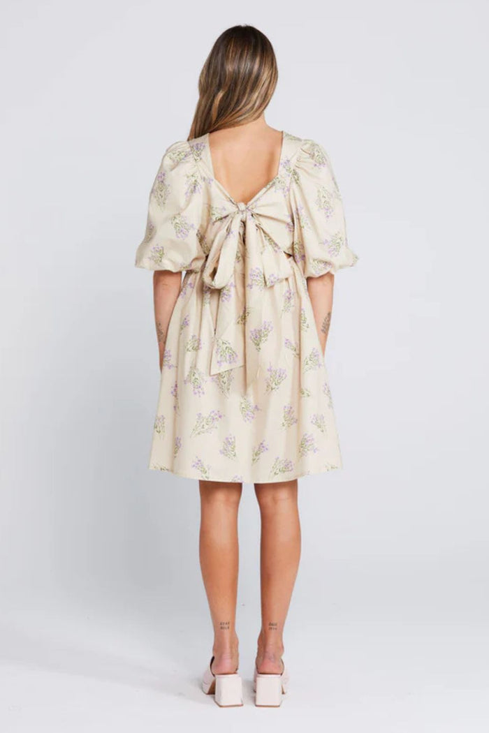 Woman wearing a cream floral mini dress with puff sleeves