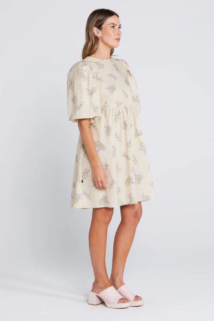Woman wearing a cream floral mini dress with puff sleeves