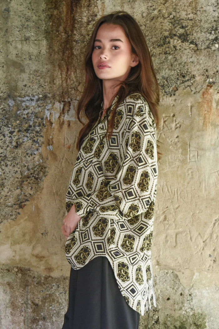 Woman wearing a patterned shawl against a textured stone wall