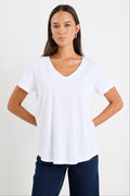 Woman wearing a white v neck top and dark blue jeans