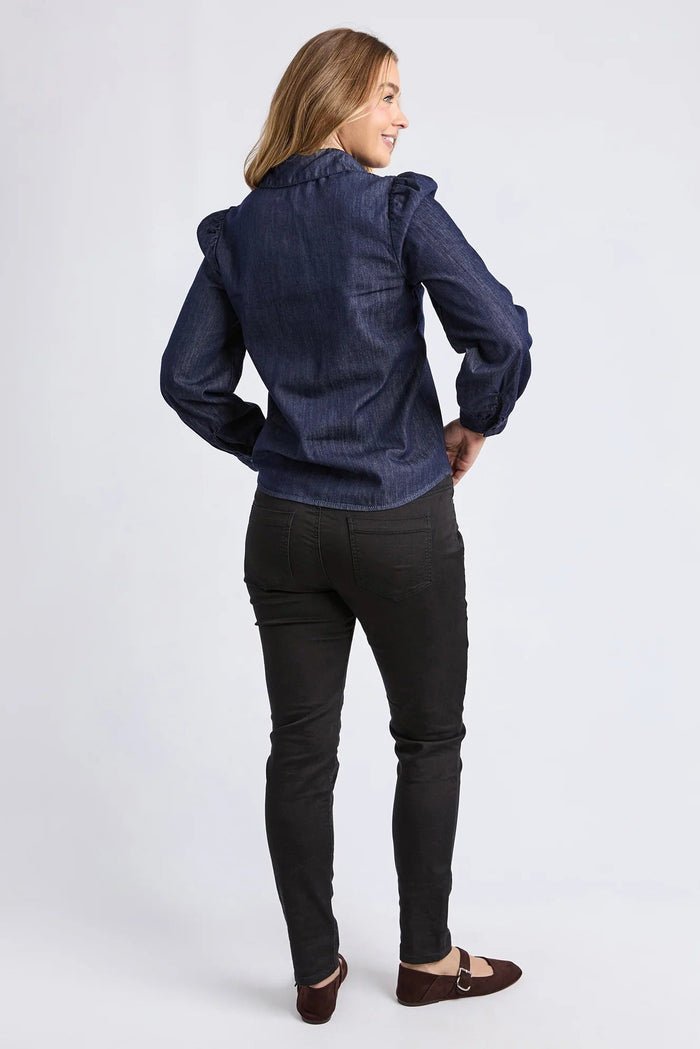 Woman wearing a blue denim shirt and black jeans on a white background