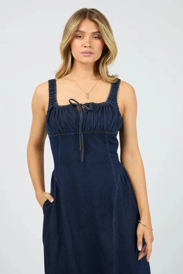 Woman wearing a navy blue dress against a plain background