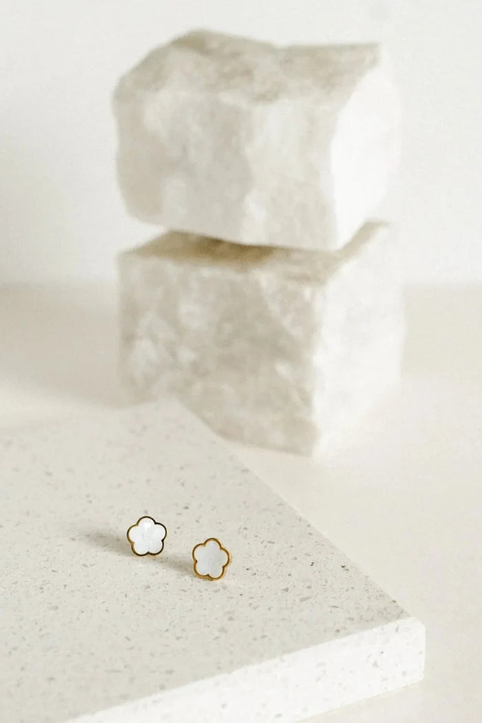 A pair of gold-toned stud earrings shaped like small flowers, featuring a pearlescent centre framed by a polished gold outline for a soft, elegant finish