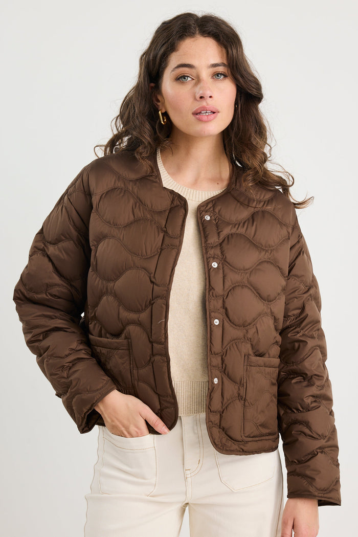 Woman wearing a brown quilted jacket on a white background