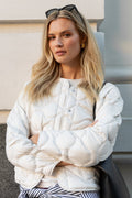 Woman wearing a white puffer jacket with a neutral background