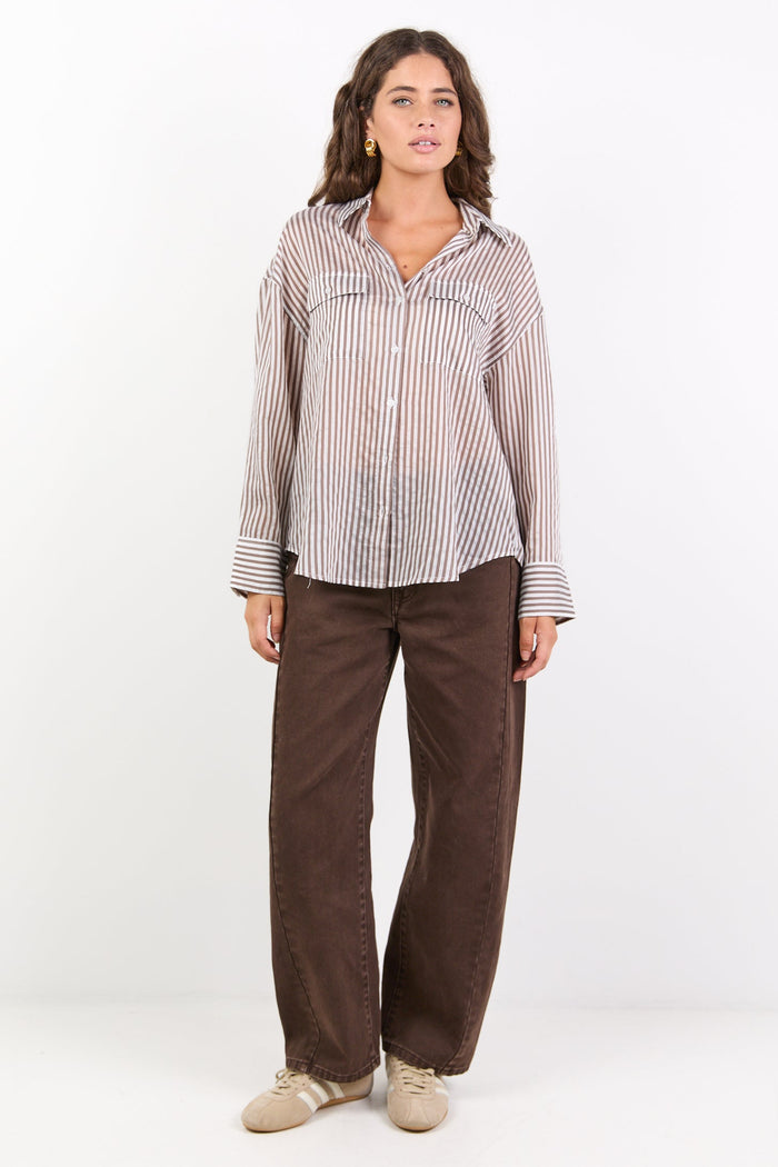 Woman wearing a checkered shirt and brown pants on a white background