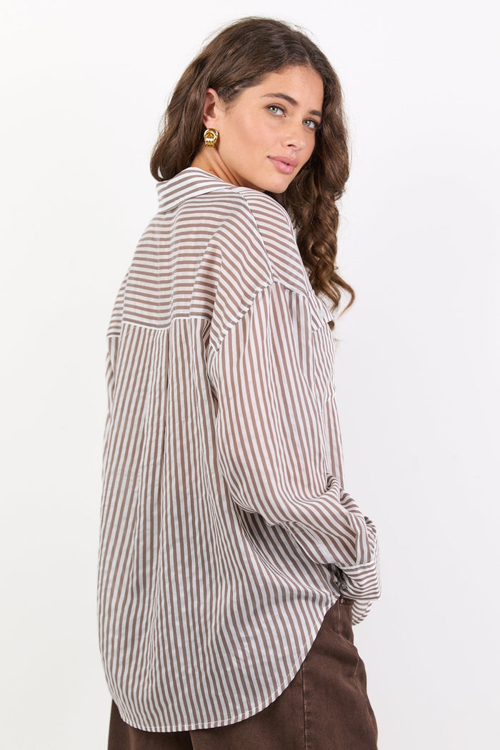 Woman wearing a striped shirt and brown pants on a white background