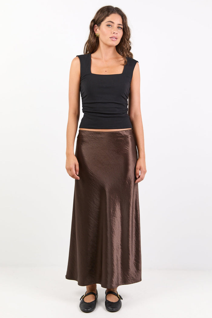 Woman wearing a black top and brown skirt on a white background