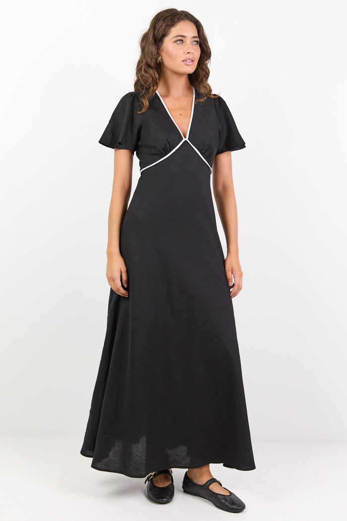 Woman wearing a black dress with white trim on a white background