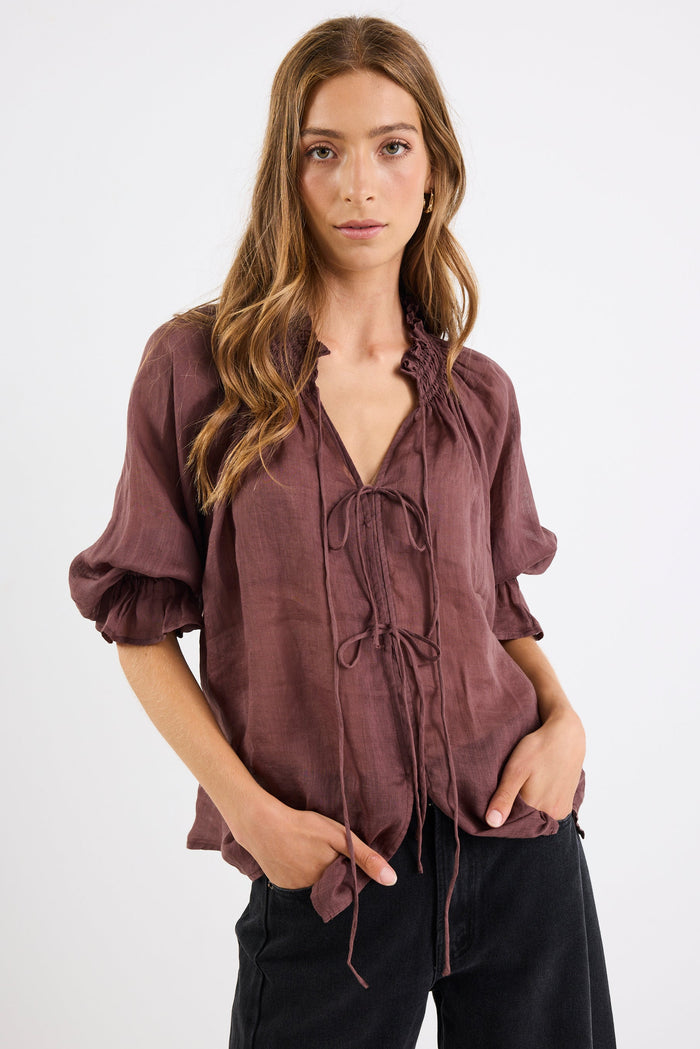 Woman wearing a brown blouse with puff sleeves on a white background