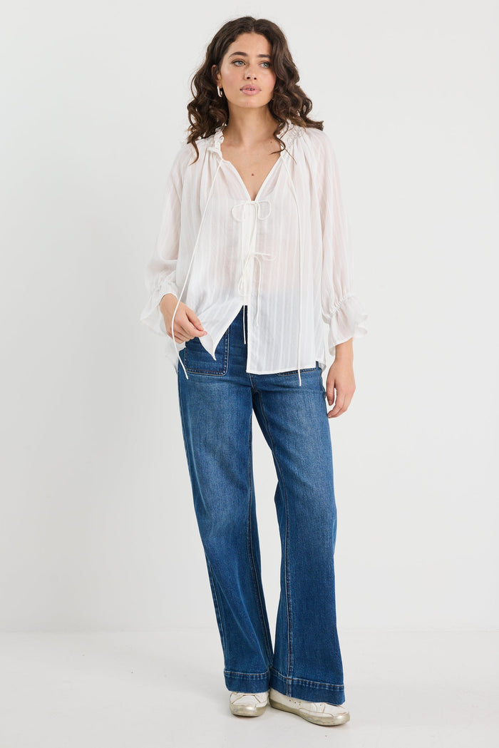 Woman wearing a white blouse and blue jeans on a white background