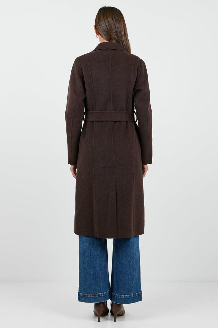 Woman wearing a brown coat and blue jeans on a white background