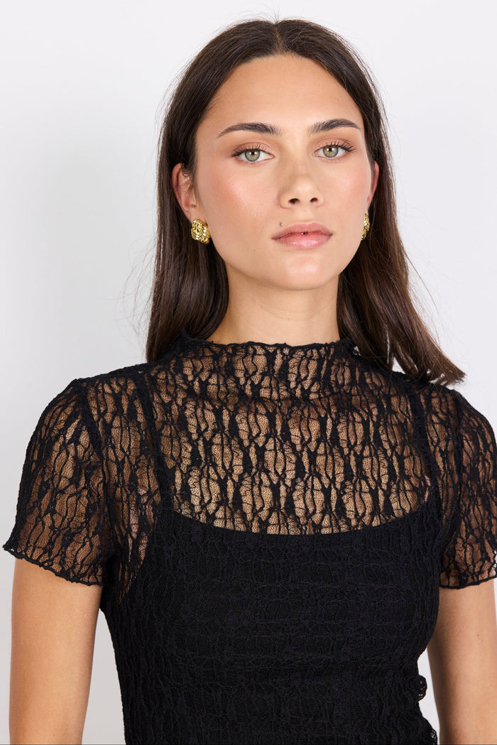 Woman wearing a black lace top against a white background