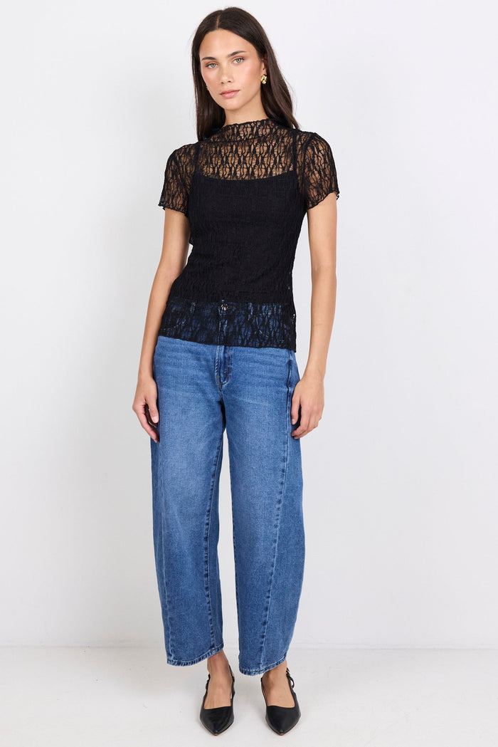 Woman wearing a black lace top and blue jeans on a white background