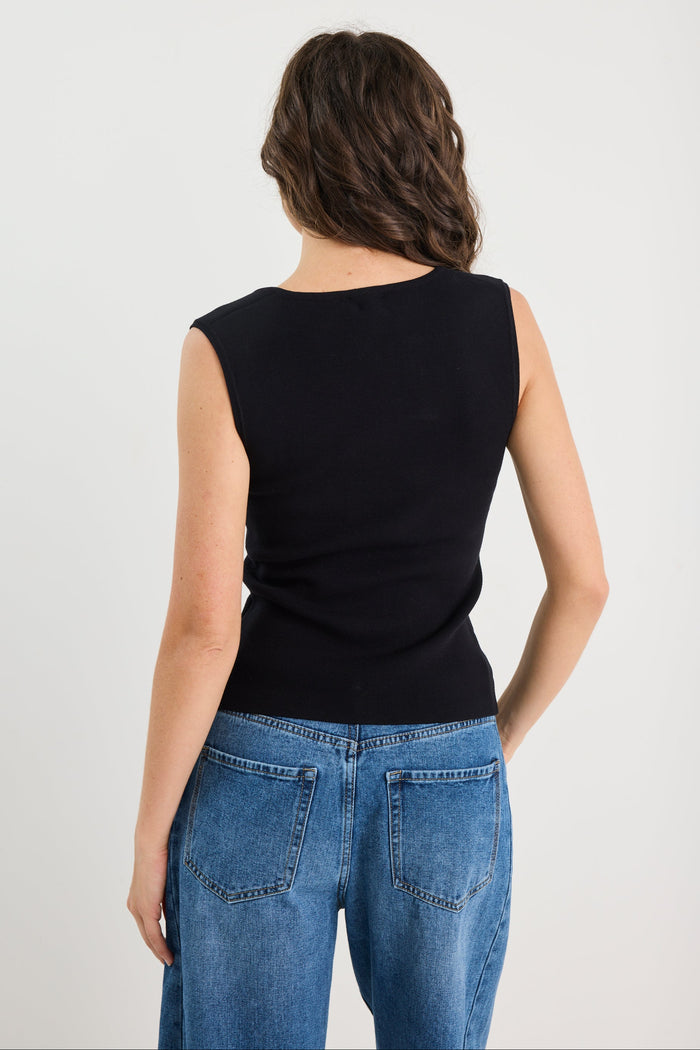 Person wearing a black sleeveless top and blue jeans on a white background
col_pattern