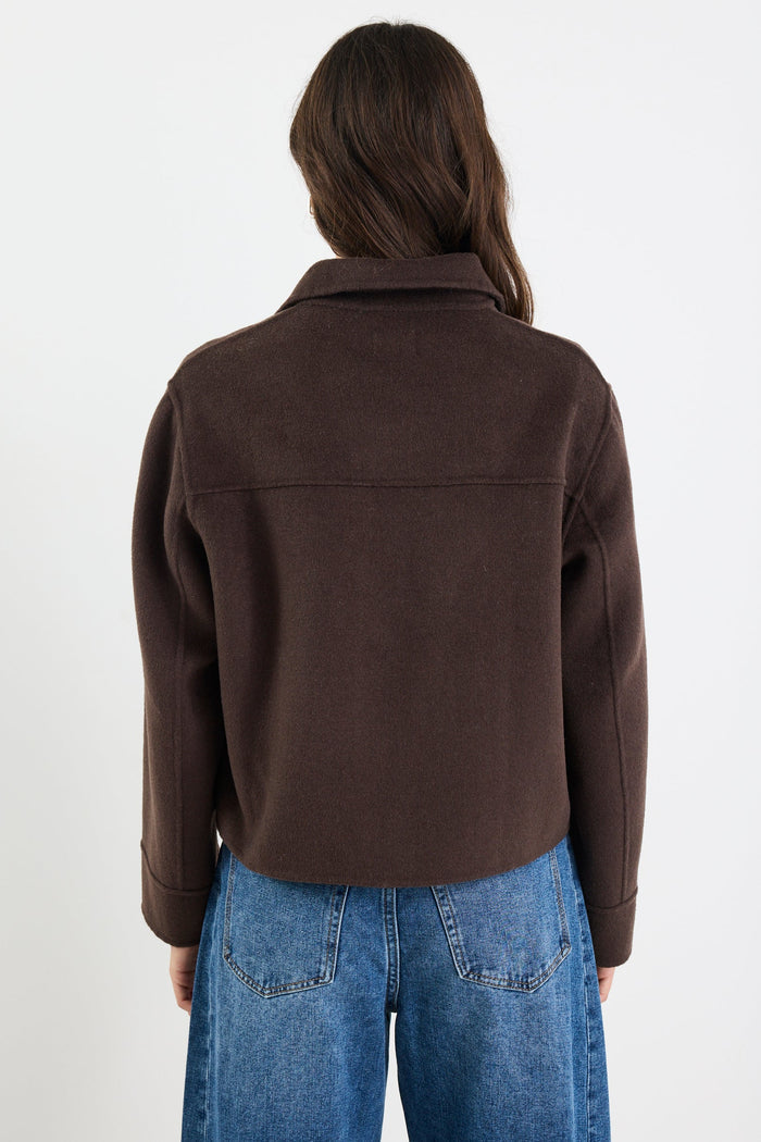 Person wearing a brown jacket and blue jeans on a white background
col_pattern