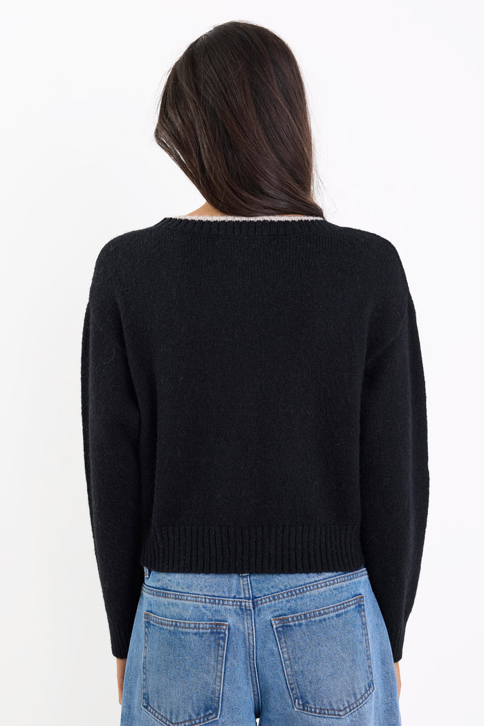Person wearing a black sweater and blue jeans on a white background
col_pattern