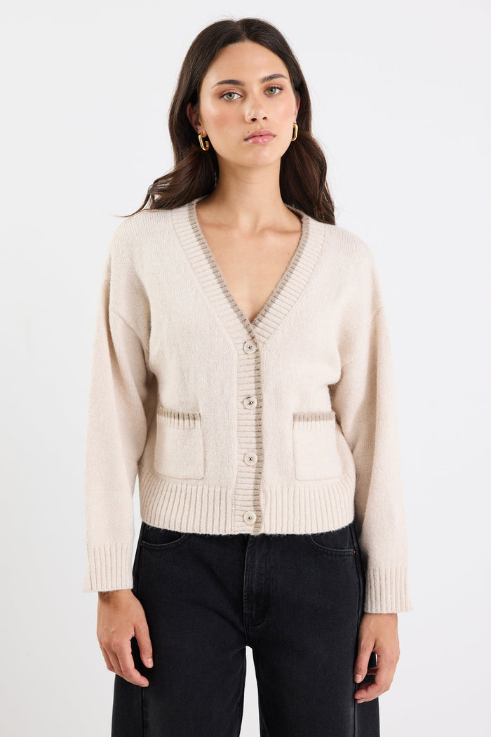 Woman wearing a beige cardigan against a white background